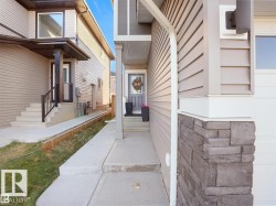 Front entryway featuring a grey door, concrete walkway, and stone-accented pillar - 
