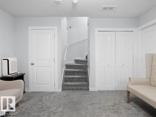 Carpeted staircase with white railing, featuring a panel door and bifold closet doors - 207 41 Avenue, Edmonton, AB 