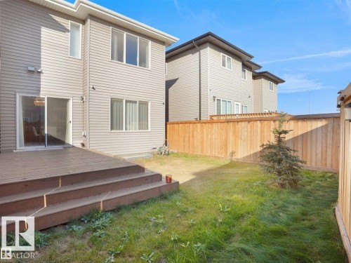 Rear exterior featuring a multi-level wood deck with steps, sliding glass patio door, and light-toned horizontal siding - 207 41 Avenue, Edmonton, AB 