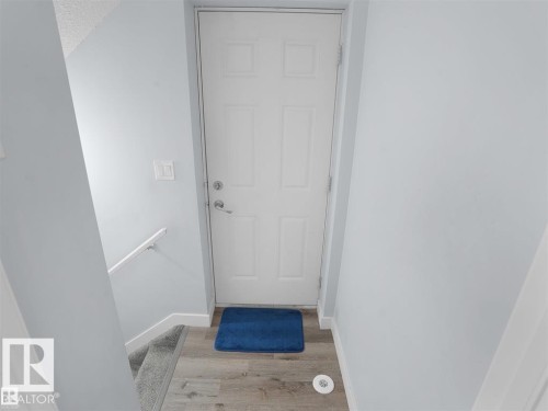 Light wood-finish flooring at the entry, complemented by white baseboards and a paneled entry door with polished hardware - 207 41 Avenue, Edmonton, AB 