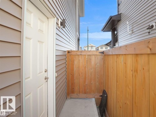 Side yard featuring a wood privacy fence with gate, concrete walkway, and exterior lighting fixtures - 207 41 Avenue, Edmonton, AB 