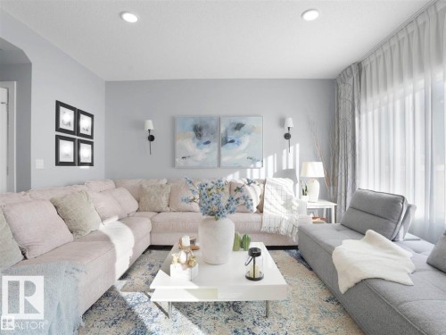 Spacious living area featuring light-toned walls, recessed lighting, and large windows with sheer drapes - 207 41 Avenue, Edmonton, AB 