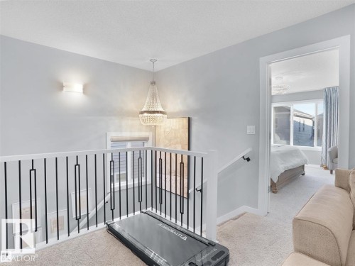 Open landing area featuring light gray walls, carpet flooring, and a modern chandelier - 207 41 Avenue, Edmonton, AB 