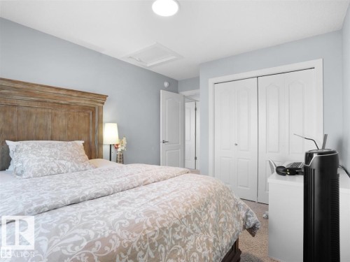 Spacious bedroom featuring light blue walls, carpet flooring, a white bi-fold closet, and a white interior door - 207 41 Avenue, Edmonton, AB 