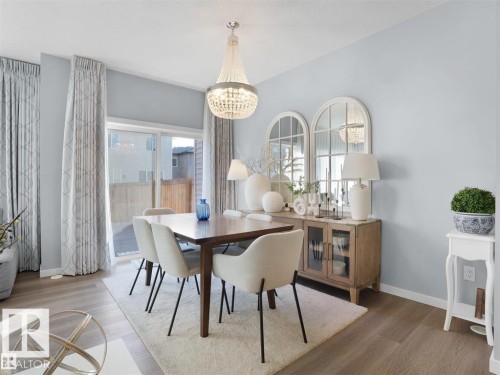 Dining area featuring wood-finish flooring, a crystal chandelier, and a sliding glass door - 207 41 Avenue, Edmonton, AB 
