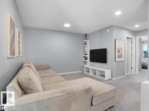 Carpeted living area featuring light gray walls, built-in shelving, a media console, and recessed lighting - 207 41 Avenue, Edmonton, AB 