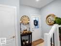Bright entryway featuring a paneled door with decorative glass, light wood-finish flooring, and a white staircase railing with black spindles - 207 41 Avenue, Edmonton, AB 