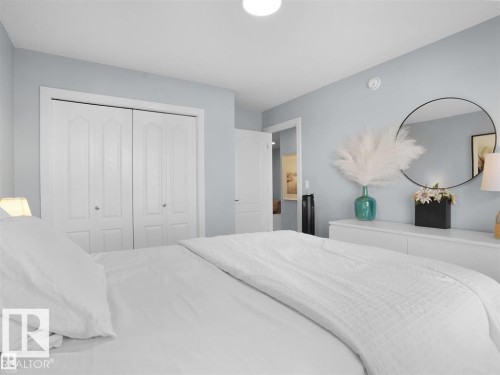 Bedroom featuring double bi-fold closet doors with white trim, light blue wall paint, and overhead flush-mount lighting - 207 41 Avenue, Edmonton, AB 