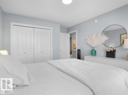 Bedroom featuring double bi-fold closet doors with white trim, light blue wall paint, and overhead flush-mount lighting - 