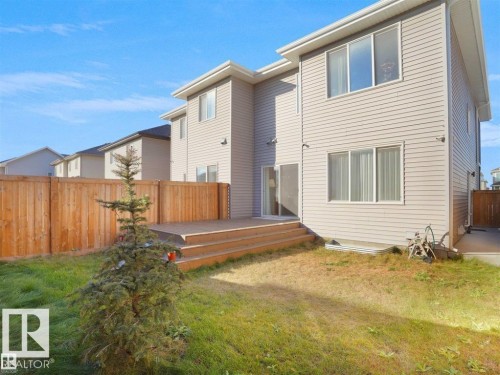 Rear exterior featuring neutral siding, a wood deck with steps, a sliding glass patio door, and multiple windows across two levels - 207 41 Avenue, Edmonton, AB 