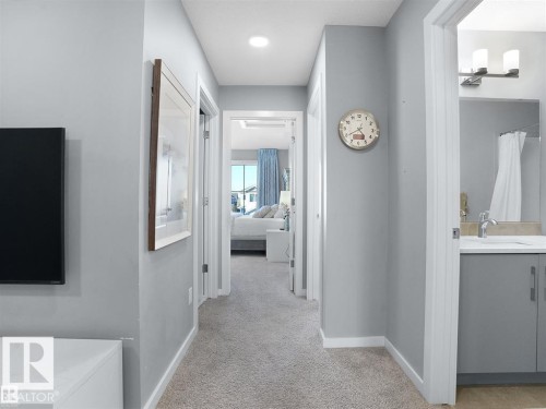 Carpeted hallway with light gray walls, leading to additional rooms - 207 41 Avenue, Edmonton, AB 