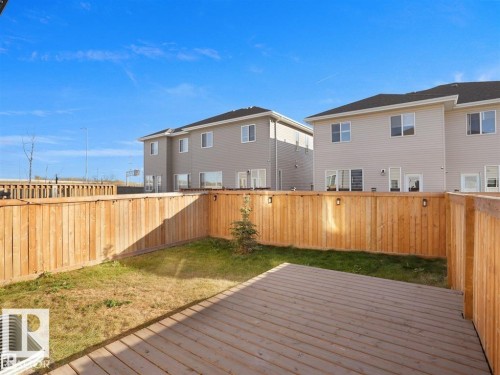 Private backyard featuring a wooden deck, a wooden privacy fence with attached lighting, and a patch of natural grass - 207 41 Avenue, Edmonton, AB 