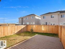 Private backyard featuring a wooden deck, a wooden privacy fence with attached lighting, and a patch of natural grass - 