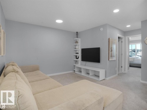 Carpeted living area featuring recessed lighting, a built-in entertainment unit, and a white corner shelving unit - 207 41 Avenue, Edmonton, AB 