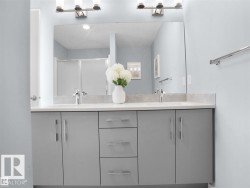 Double vanity with gray cabinetry, brushed nickel hardware, and light-toned countertops - 