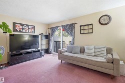 Living area featuring carpet flooring, light-toned walls, and a sliding glass door providing access to an outdoor space - 