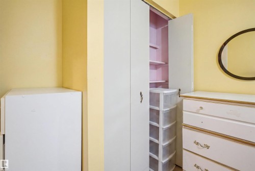 Built-in closet with bifold doors, integrated shelving, and brass hardware - 17 Lakewood Village, Edmonton, AB 