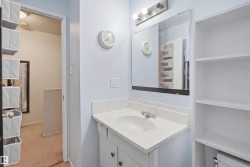 Bathroom vanity featuring a white countertop with an integrated sink, a large wall-mounted mirror, and a three-bulb vanity light fixture - 