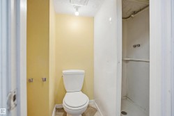 Bathroom featuring a floor-mounted toilet, light yellow painted walls, and a white shower stall with a built-in shelf - 