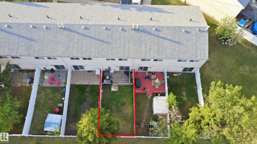 Rear exterior of a townhouse featuring a private fenced yard with mature trees - 17 Lakewood Village, Edmonton, AB 