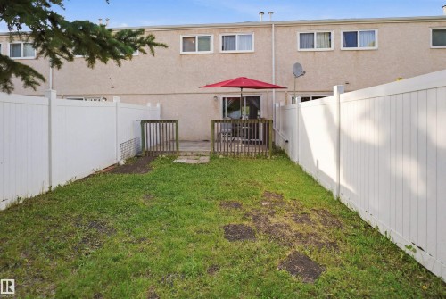 Enclosed backyard space featuring a patio, a wooden deck, and white privacy fencing - 17 Lakewood Village, Edmonton, AB 