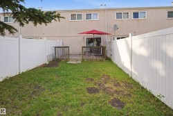 Enclosed backyard space featuring a patio, a wooden deck, and white privacy fencing - 