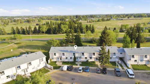 Row of townhomes featuring light-colored exteriors, individual front entrances, and an integrated parking area - 17 Lakewood Village, Edmonton, AB 