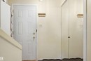 Entryway featuring a paneled door with brass hardware and a mirrored closet - 17 Lakewood Village, Edmonton, AB 