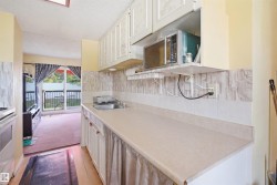 Kitchen with white cabinetry, a single-basin stainless steel sink, and a light-toned countertop - 