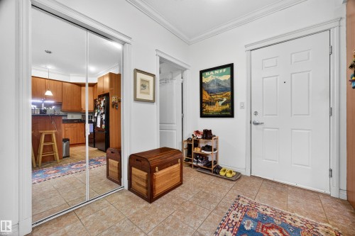 Entryway featuring ceramic tile flooring, a paneled entry door, crown molding, and a mirrored closet - 304 10116 80 Avenue, Edmonton, AB 