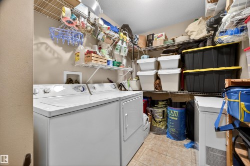 Dedicated laundry area featuring a washer and dryer, tile flooring, and multiple wire shelving units for storage - 304 10116 80 Avenue, Edmonton, AB 