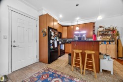 Functional kitchen featuring wood cabinetry, black appliances, a breakfast bar, and tile flooring - 