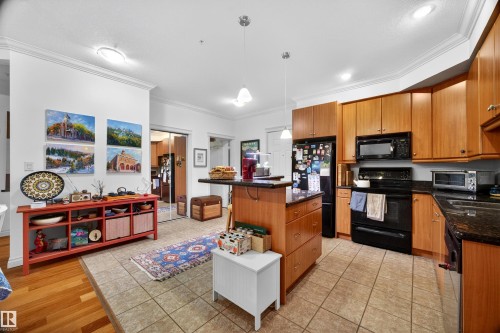 Kitchen featuring wood cabinetry, black appliances, dark countertops, and tile flooring - 304 10116 80 Avenue, Edmonton, AB 