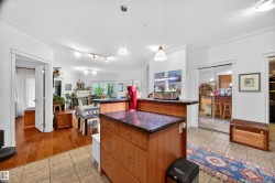 Kitchen island with a dark granite-style countertop and wood-finish cabinetry - 