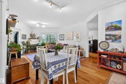 Open concept living area featuring wood-finish flooring, white walls, crown molding, a fireplace with a white mantel, and a large window - 