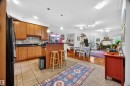 Kitchen featuring wood cabinetry, dark countertops, and a patterned tile backsplash - 304 10116 80 Avenue, Edmonton, AB 