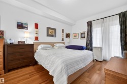 Bedroom featuring wood-finish flooring, a light wood bed frame, and white walls - 