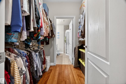 Walk-in closet featuring wood-finish flooring, built-in shelving, and hanging storage - 304 10116 80 Avenue, Edmonton, AB 