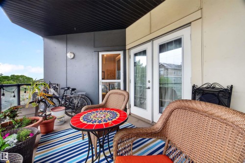 Outdoor balcony with concrete flooring, framed by a dark gray exterior wall and an off-white wall - 304 10116 80 Avenue, Edmonton, AB 