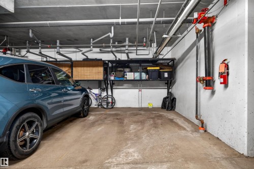 Concrete floor parking space featuring exposed ceiling utilities - 304 10116 80 Avenue, Edmonton, AB 