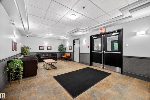 Spacious common area featuring durable tile flooring, wainscoting, and recessed lighting - 304 10116 80 Avenue, Edmonton, AB 