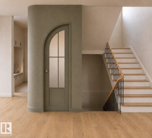 Open concept entry area featuring wood-finish flooring, a curved wall with an arched door, and a staircase with a wood handrail and black iron balusters - 9243 148 Street, Edmonton, AB 