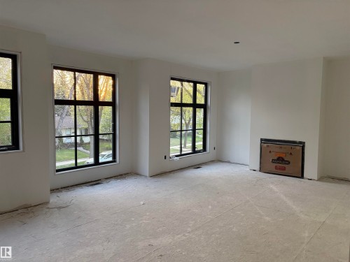 Spacious room featuring multiple large windows with dark frames, a recessed fireplace installation, and light-colored walls - 9243 148 Street, Edmonton, AB 
