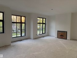 Spacious room featuring multiple large windows with dark frames, a recessed fireplace installation, and light-colored walls - 