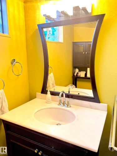 Bathroom vanity featuring a white oval sink, chrome faucet, and a light-toned countertop - 15003 81 Street, Edmonton, AB 
