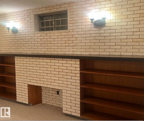 Brick-look accent wall featuring a built-in fireplace and integrated shelving - 15003 81 Street, Edmonton, AB 