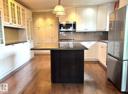 Central kitchen island with dark cabinetry and a polished countertop - 15003 81 Street, Edmonton, AB 