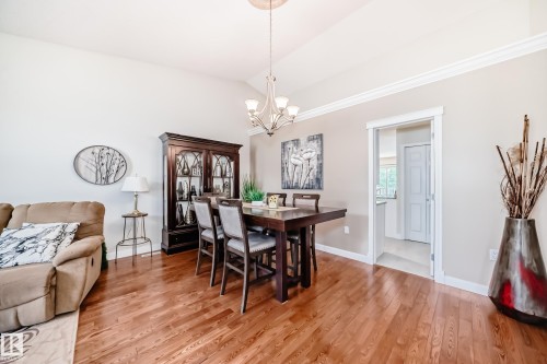 Dining area with wood-finish flooring, crown molding, and a chandelier - 50 303 Twin Brooks Drive Nw, Edmonton, AB 