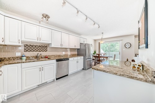 Kitchen featuring white cabinetry, light-toned tile flooring, and speckled countertops - 50 303 Twin Brooks Drive Nw, Edmonton, AB 