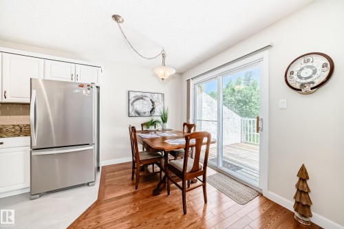 Dining area featuring wood-finish flooring, a contemporary pendant light fixture, and white wall finishes - 50 303 Twin Brooks Drive Nw, Edmonton, AB 